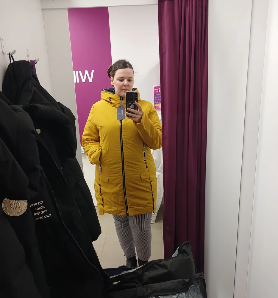 Фасон действительно стройнит, как и пишет продавец. Курточка лёгкая,  яркая, материал приятный на ощупь. Единственное, что меня смутило, это отделка изнанки по видимому краю очень блестящей гладкой чёрной тканью, похожей по моему мнению более всего на мусорный пакет. Сначала даже разочаровалась из-за этого, но села куртка на порядок лучше остальных, поэтому выбрала её. И после пары недель носки мне она очень нравится. Особенно люблю двойную молнию. Она очень аккуратно выполнена и работает великолепно, расстегнуться можно за одно движение на ходу одной рукой. У нас было за это время и -10 и +10 - в ней мне было комфортно. И блестящая подкладка уже не бесит- она очень мягкая оказалась) спасибо продавцу!