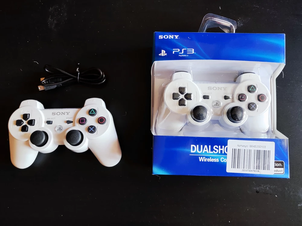 С виду неплохая реплика DualShock 3 (на фото белый - от магазина, чёрный - оригинал). Её, конечно, сразу выдают кривые надписи, но я брал просто как запасной вариант и для игры вчетвером для непривередливой компании. Консолью определяется нормально, в тесте геймпада все кнопки прлжимаются, но триггеры L2 и R2 имеют большую мёртвую зону, фронтальные кнопки не реагируют на силу нажатия. Стики, вроде, адекватно работают, пока не жалуюсь. Гироскоп, вроде как, рабочий, но насколько точный не скажу, просто в тестовой программе поглядел. В целом, хороший вариант за небольшие деньги, на мой взгляд. Поглядим как дальше себя поведут!